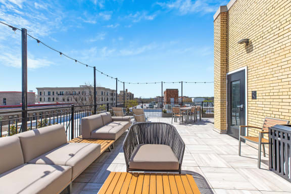 a rooftop deck with couches and tables on a sunny day