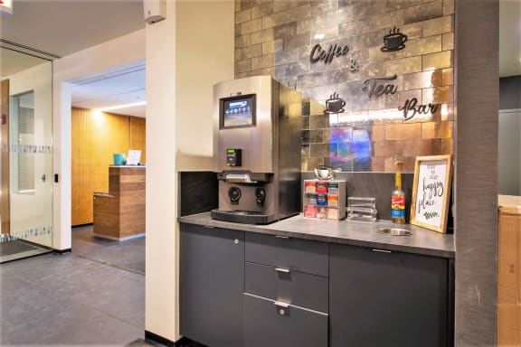 a counter with a coffee machine and a sink in front of a brick wall