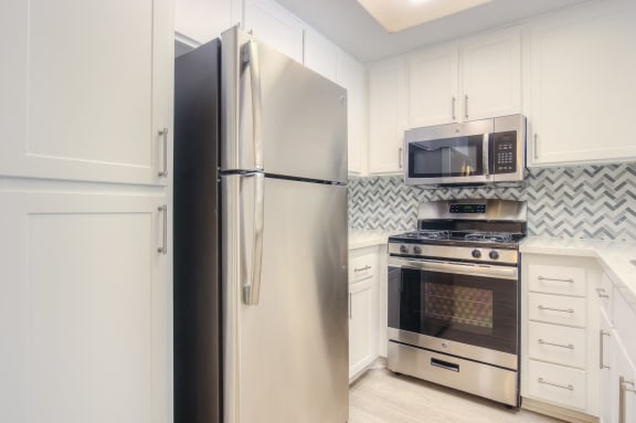 Renovated kitchen featuring white cabinet, countertops and stainless steel appliances.