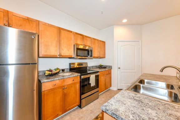 Open Kitchen with Custom Maple Cabinets, Stainless Steel Appliances and Breakfast Bar at Alden Place at South Square Apartments, Durham, NC 27707