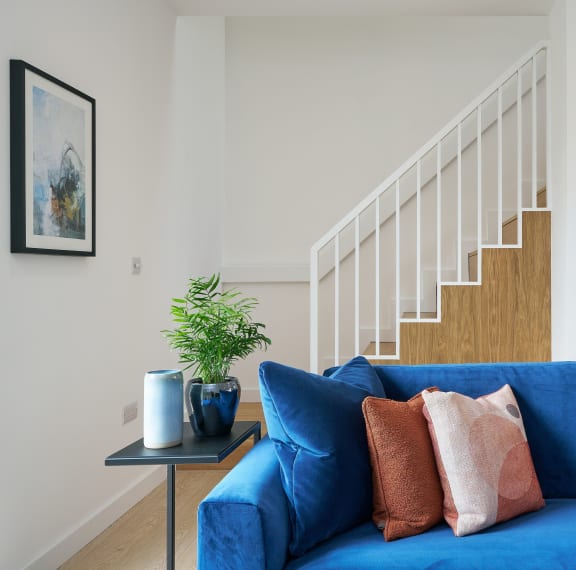 a living room with a blue couch and a small table with a plant on it