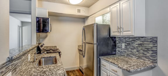 Apartments in Dallas-Paxton at Lake Highlands Kitchen with Matching Appliances, Gorgeous Tile Backsplash, and Hardwood Floors