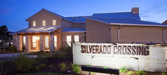 Evening entrance with office and monument sign Silverado Crossing Apartments For Rent  l Buda Texas 78610
