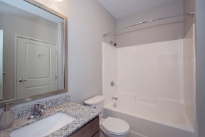 Spacious Bathroom with Granite Countertop Vanity and Shower with Tub