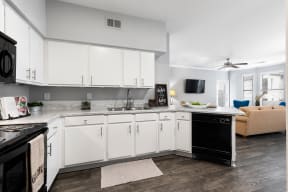 Kitchen with white cabinets, dishwasher, stove, microwave, granite countertops