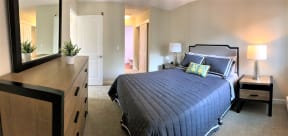one bedroom model with queen size bed, drawers, side tables. short hallway closet walkway to bathroom