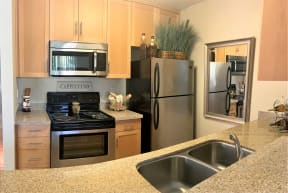 2 bedroom model  kitchen with black/stainless steel appliances such as refrigerator, microwave and stove/oven