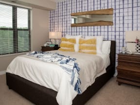 Furnished bedroom with queen bed, blue patterned accent wall and nightstand