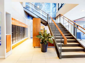 Lobby entrance with staircase on right and hallway with mail lockers on right
