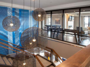 View from top of lobby staircase, decorative light fixtures hanging from ceiling and shuffleboard table in adjacent room