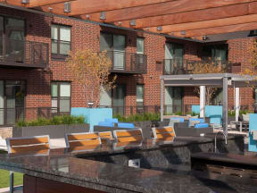 Outdoor community kitchen and bar with seating, balconies in background