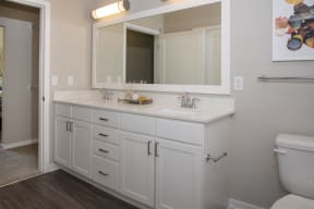 Sleek bathroom with white cabinet vanity, designer finishes, large mirror, and dual sinks.