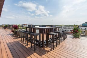 Rooftop grill area with several grills and high table with chairs
