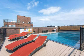 Outdoor rooftop swimming pool next to sundeck with orange sunning chairs