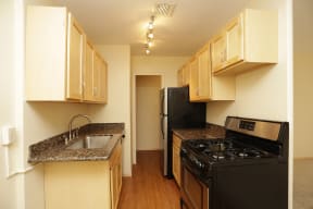 Full kitchen with light wood cabinets, black appliances, and granite countertops