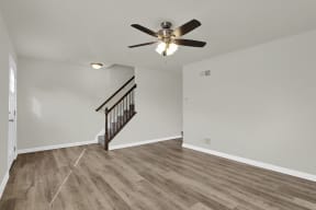 living room with hardwood floors and ceiling fan stairs leading up to the third level