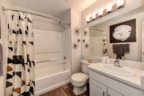 Bathroom with Wood Inspired Floors, Toilet, Patterned Shower Curtain and Vanity