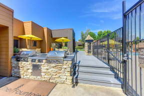 BBQ Area with Yellow Umbrellas, Grills, Gates with View of Pool