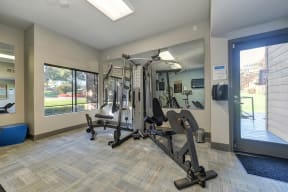 Fitness center entrance.  Room has large weight systems, carpeting, mirrors and several windows.