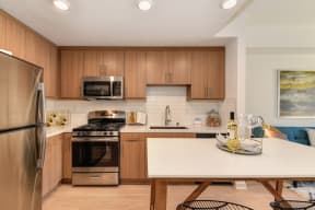 Model home kitchen with stainless steel appliances and light brown cabinetry  