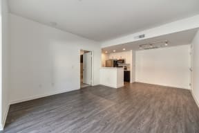 Vacant apartment living room with hardwood inspired flooring and views of the kitchen