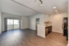 Vacant apartment living room with hardwood inspired flooring and views of the kitchen