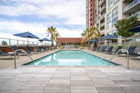 Apartments in San Jose, CA - Sparkling Swimming Pool Surrounded By Lounge Seating and Exterior View of Centerra Apartments Building