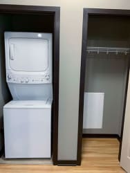 Stacked washer and dryer in closet next to extra storage closet