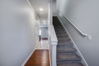 Hallway With Wood-Style Flooring & Carpeted Stairwell Going Upstairs