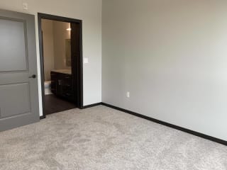 Carpeted bedroom with door to the walk in closet and door to the bathroom