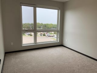 Carpeted bedroom with large floor to ceiling window looking out to north Lincoln