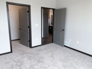 Carpeted bedroom with door to the walk in closet and door to the bathroom