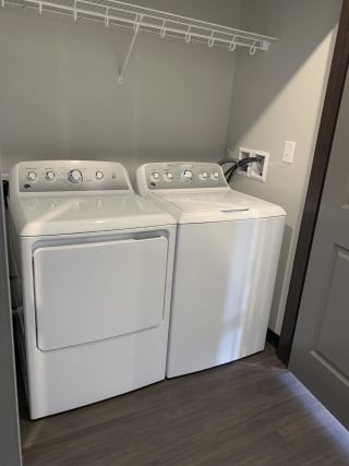 Full sized washer and dryer with rod and shelf above for storage at Haven at Uptown