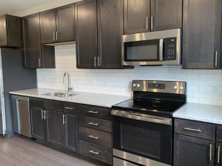 Kitchen with dark brown cabinets and matching stainless steel appliances in Peace floorplan at Haven at Uptown
