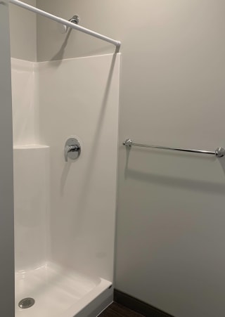 Walk-in shower with curtain rod and towel rack near by at Haven at Uptown