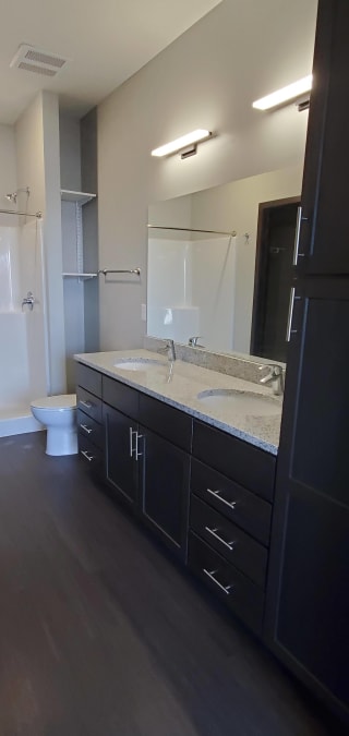 Bathroom with dark brown bathroom vanity with light granite and dual vanities and linen closest