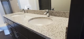 Light speckled granite bathroom counter with two side-by-side sinks
