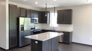 Haven-at-Uptown-Lincoln-NE-2-bedroom-apartment-Aura-Mocha-finish-20 Kitchen with dark brown mocha cabinets, stainless steel appliances and island