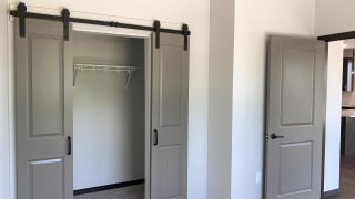 Haven-at-Uptown-Lincoln-NE-2-bedroom-apartment-Aura-Mocha-finish-23 Bedroom with walk in closet enclosed by sliding barn door