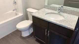 Bathroom with dark brown cabinets and light granite counters with undermount sink