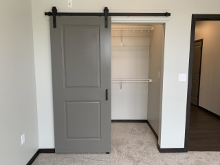 Walk in closet with sliding barn door and shelves for clothes and shoe storage