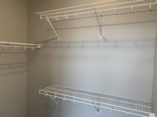 Walk in closet with multiple wire wall mount shelves for clothing and shoe storage