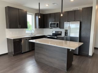 Large kitchen with warm dark brown cabinets, stainless steel appliances, and an island with extra storage