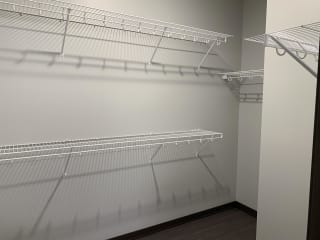 Walk in closet with multiple wire wall mount shelves for clothing and shoe storage