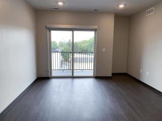 Empty living area with wood floors and sliding door leading to patio