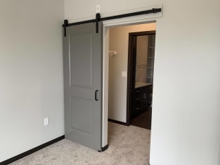 Open barn door looking into a pass through walk in closet in a one bedroom apartment in Lincoln