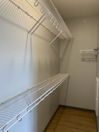 Large empty walk in closet with upper and lower wire racks for clothing storage