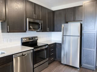 corner of kitchen with stainless steel appliances and warm brown cabinets for storage
