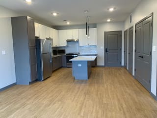 Open kitchen to dining room with large granite countertop island at Haven at Uptown in Lincoln, Nebraska
