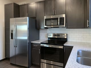 Kitchen with dark brown cabinets and large kitchen island and matching stainless steel appliances